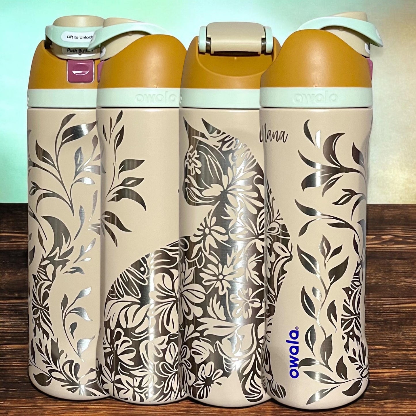 Owala Freesip 24oz water bottle with intricate full-wrap detailed floral cat engraving in water in the desert color