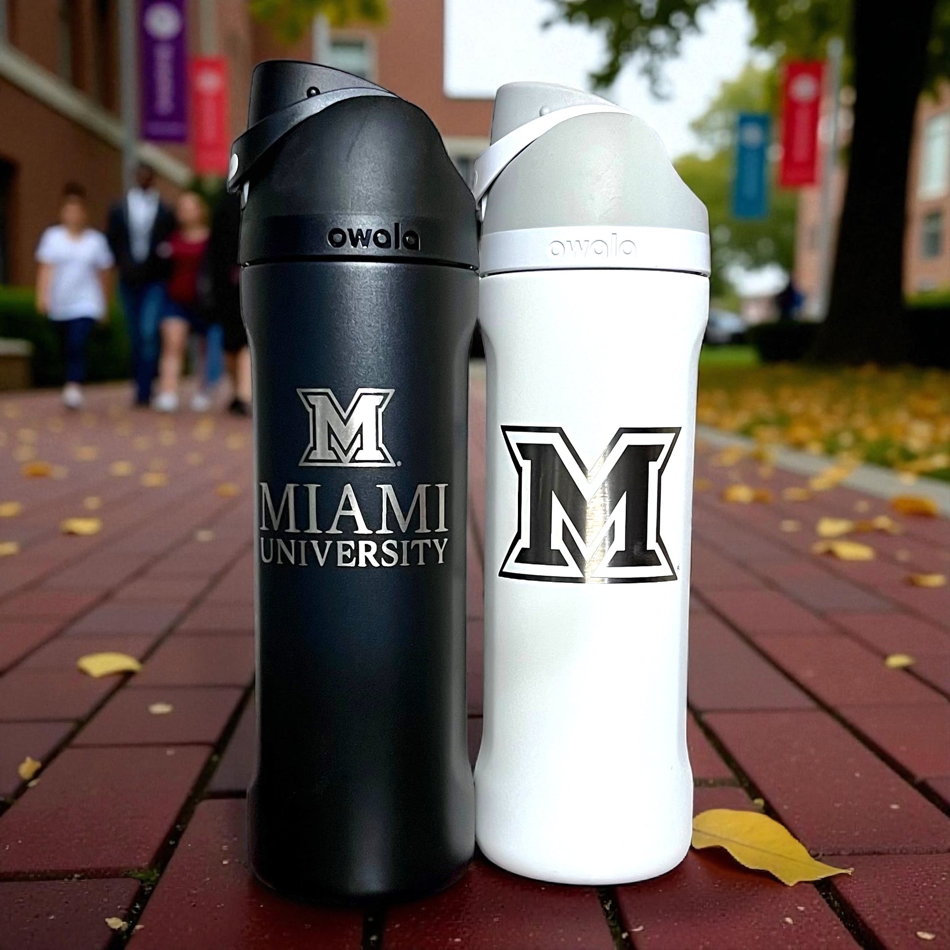 Two insulated water bottles with 'Miami University' logo on a brick surface.