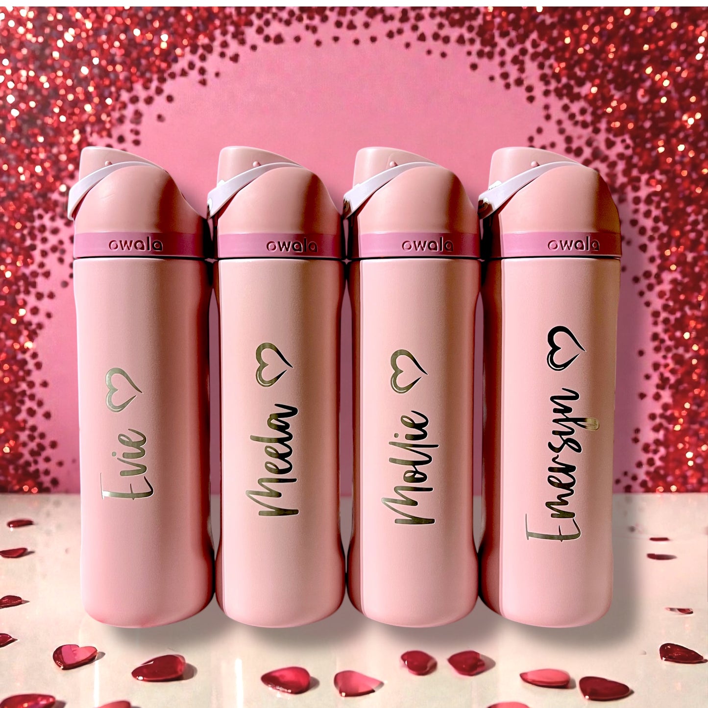 Four pink Owala water bottles with names on a glittery pink background